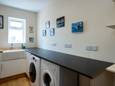 A laundry room with a sink washing machines and wall decorations at Flaad House in Rock