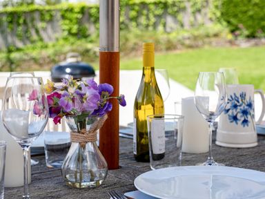 An outdoor dining table set with wine glasses a bottle a vase with flowers plates and a pitcher at Flaad House in Rock