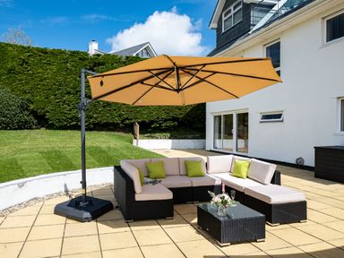 An outdoor patio with a sectional sofa with cushions and a large umbrella at Flaad House in Rock