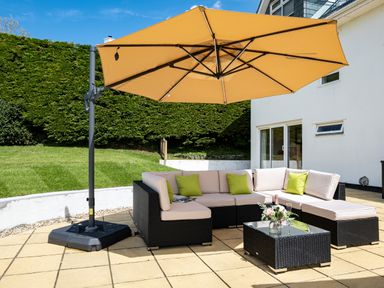 A patio with a sectional sofa, coffee table, large umbrella, and green lawn at Flaad House in Rock