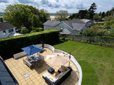 A backyard patio with outdoor dining and seating areas under umbrellas next to a lawn at Flaad House Rock