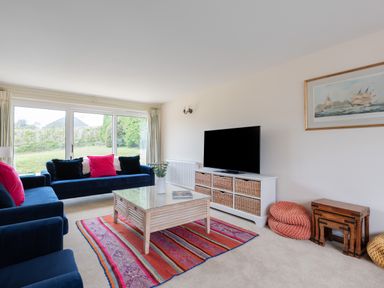 A living room with blue sofas pink cushions a wooden coffee table a colorful rug and a television at Flaad House in Rock