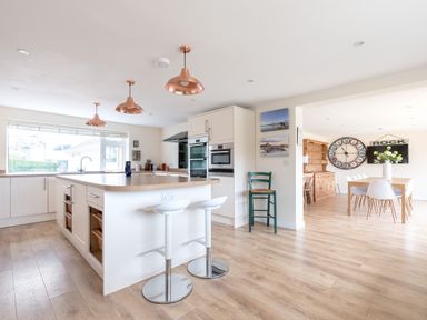 A kitchen with a large island with stools and dining area with wooden table and chairs at Flaad House in Rock
