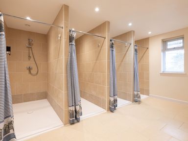 A bathroom with multiple tiled shower stalls and striped shower curtains at Flaad House in Rock