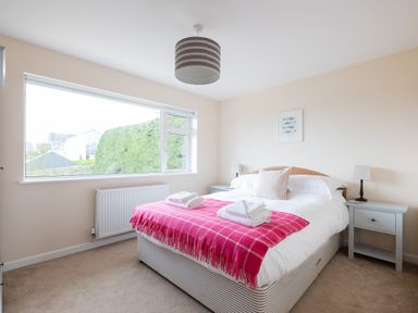 A bedroom with a double bed a pink blanket and towels on the bed beside two grey nightstands with lamps at Flaad House in Rock
