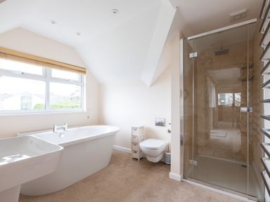 A bathroom with a freestanding bathtub a shower enclosure a wall-mounted toilet and a window at Flaad House in Rock
