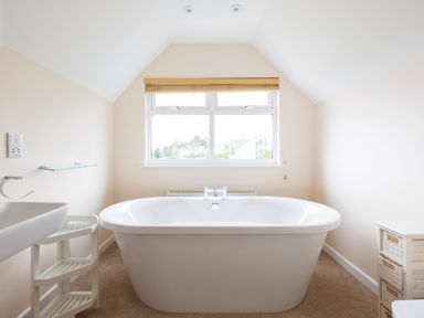 A bathroom with a standalone bathtub below a window and shelving units on each side at Flaad House Rock