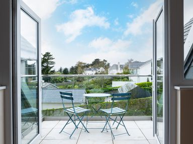 A balcony with a round table and two chairs overlooking houses and trees at Flaad House in Rock