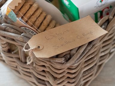 A wicker basket with biscuits and a PG tips tea box with a welcome note at Swallow Cottage in Port Isaac
