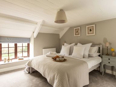 A bedroom with a double bed pillows bedside tables and a window with a view at Swallow Cottage in Port Isaac