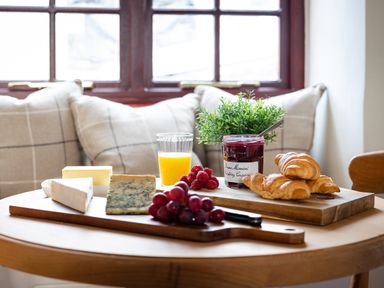 A breakfast table with croissants berries cheese butter jam and orange juice in a kitchen area at Swallow Cottage in Port Isaac
