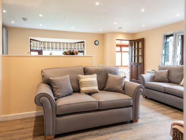 A living room with two grey sofas and a wooden floor at Brookside in Polzeath