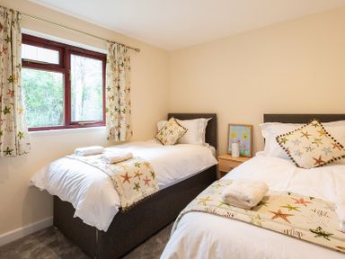 A bedroom with two single beds with starfish patterned bedding and curtains at Brookside in Polzeath