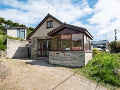 A house with a stone and brick exterior and a gravel driveway at Brookside in Polzeath
