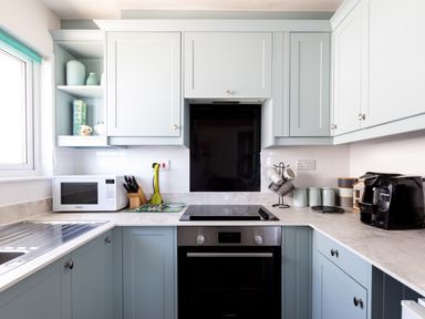 A kitchen with blue cabinets a microwave stove coffee machine and utensils at Gulland Port Isaac