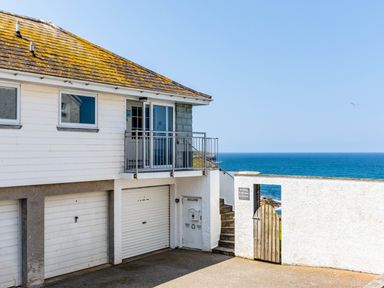 Exterior of a building with garage doors a balcony and a gate overlooking the sea at Gulland in Port Isaac
