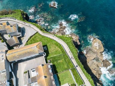 A coastal area with buildings near a road and a rocky shoreline at Gulland in Port Isaac