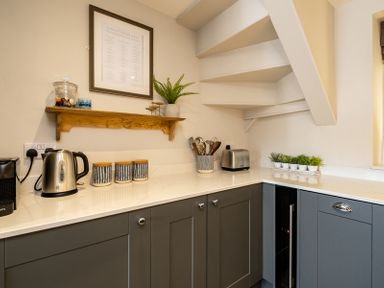 A kitchen counter with kettle toaster jars shelf and utensils at Mino Cottage in Port Isaac