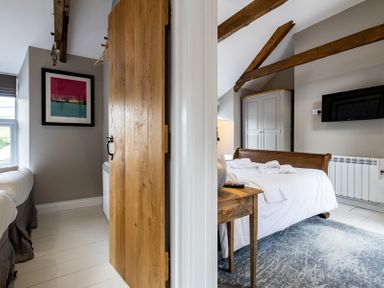 A bedroom with a wooden bed table and TV and another bedroom with a framed picture at Mino Cottage Port Isaac