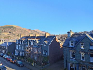 A street with parked cars and terraced houses with hills in the background at Squirrel Lodge in Keswick