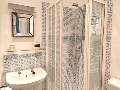 A bathroom with a sink mirror and a shower enclosure with patterned tiles at Squirrel Lodge in Keswick