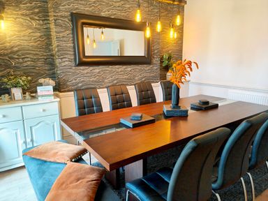 A dining room with a wooden table surrounded by black chairs and a bench with brown cushions at Squirrel Lodge in Keswick