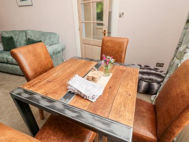 A dining area with a wooden table and brown chairs beside a green sofa at Islestone 1 Temperance Terrace in Berwick-Upon-Tweed