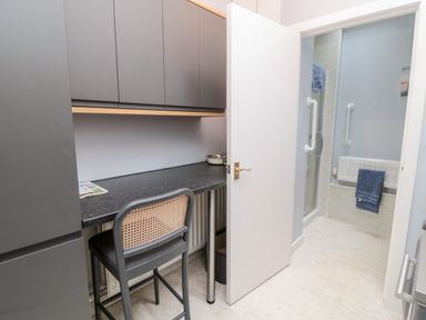 A room with a black countertop and a chair next to cabinets and an open door revealing a bathroom with towels at Islestone 1 Temperance Terrace in Berwick-Upon-Tweed