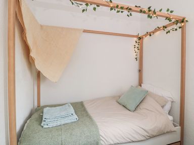 A bed with wooden frame draped with fabric and decorative lights at Islestone 1 Temperance Terrace in Berwick-Upon-Tweed