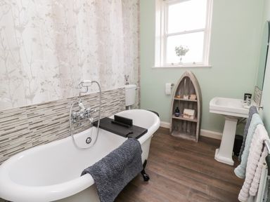 A bathroom with a bathtub a sink a toilet and a boat-shaped shelf at Islestone 1 Temperance Terrace in Berwick-Upon-Tweed
