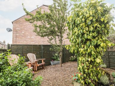 A small garden area with two wooden chairs gravel ground and green plants at Islestone 1 Temperance Terrace in Berwick-Upon-Tweed