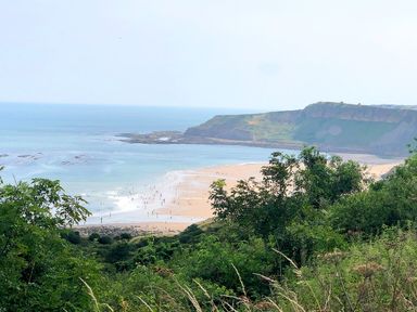 A coastal landscape showing a beach with people near the water and hills in the background at Meadow Lodge in Cayton
