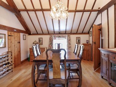 A dining room with wooden table and chairs under a chandelier at The Old Custom House in Wangford