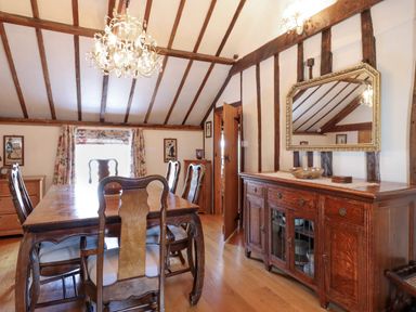 A dining room with wooden table and chairs a chandelier and a sideboard with mirror at The Old Custom House in Wangford