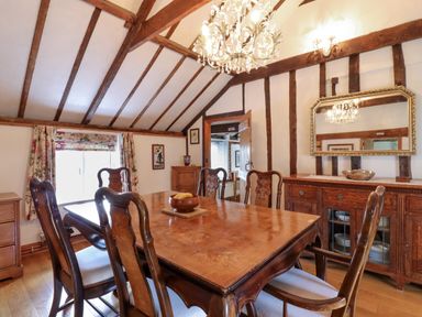 A dining room with a wooden table and chairs a chandelier and a sideboard with a mirror at The Old Custom House in Wangford