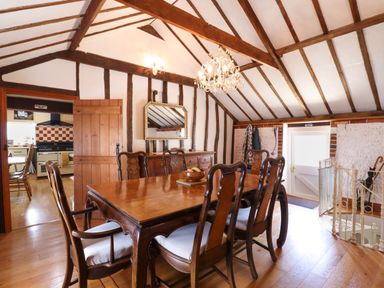 A dining room with a wooden table and chairs under exposed wooden beams at The Old Custom House in Wangford