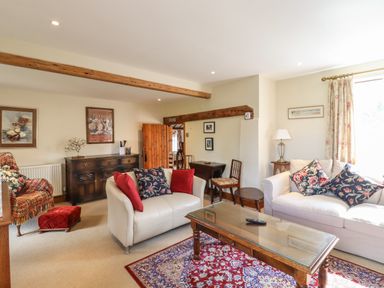 A living room with two sofas a wooden coffee table a wooden sideboard and framed pictures on the wall at The Old Custom House in Wangford