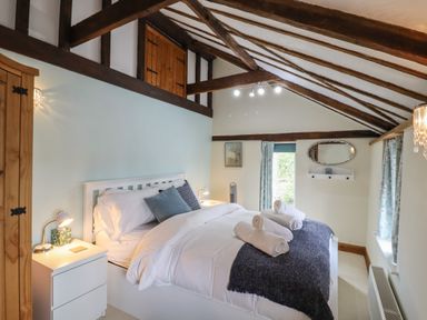A bedroom with a white bed and nightstands under exposed wooden beams at The Old Custom House in Wangford