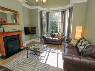 A living room with brown leather sofas a glass coffee table a fireplace and a wall mounted tv at South Bay House in Scarborough