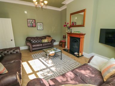 A living room with brown leather sofas a glass coffee table and a fireplace at South Bay House in Scarborough