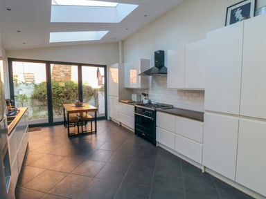 A kitchen with white cabinets black stove wooden table and large glass doors at South Bay House in Scarborough