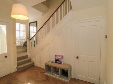 A hallway with stairs carpeted steps a bench with compartments a pillow a mirror and doors at South Bay House Scarborough