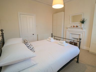 A bedroom with a double bed towels on the bed wardrobes and a fireplace at South Bay House in Scarborough
