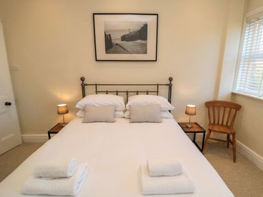 A bedroom with a double bed, two bedside tables with lamps, a wooden chair, and a framed picture above the bed at South Bay House in Scarborough