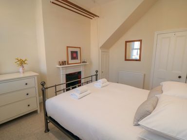 A bedroom with a bed with folded towels a white dresser and a fireplace at South Bay House in Scarborough