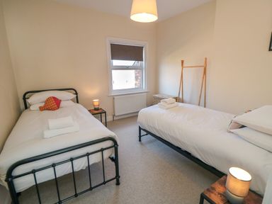 A bedroom with two single beds a window and lamps at South Bay House Scarborough
