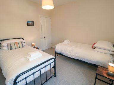 A bedroom with two single beds a nightstand with a lamp and a door at South Bay House in Scarborough