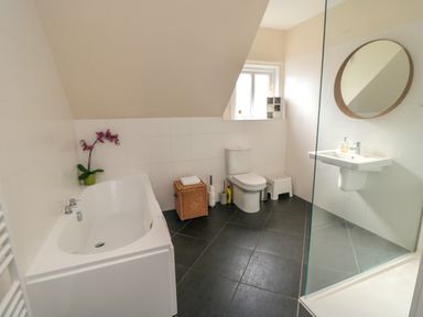 A bathroom with a bathtub toilet sink round mirror and window at South Bay House in Scarborough