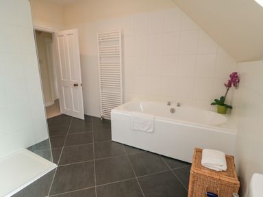 A bathroom with a bathtub a towel rack and a wicker basket with folded towels at South Bay House in Scarborough