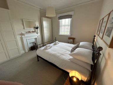 A bedroom with a metal bed frame white bedding folded towels on bed white wardrobes a fireplace and a window at South Bay House in Scarborough